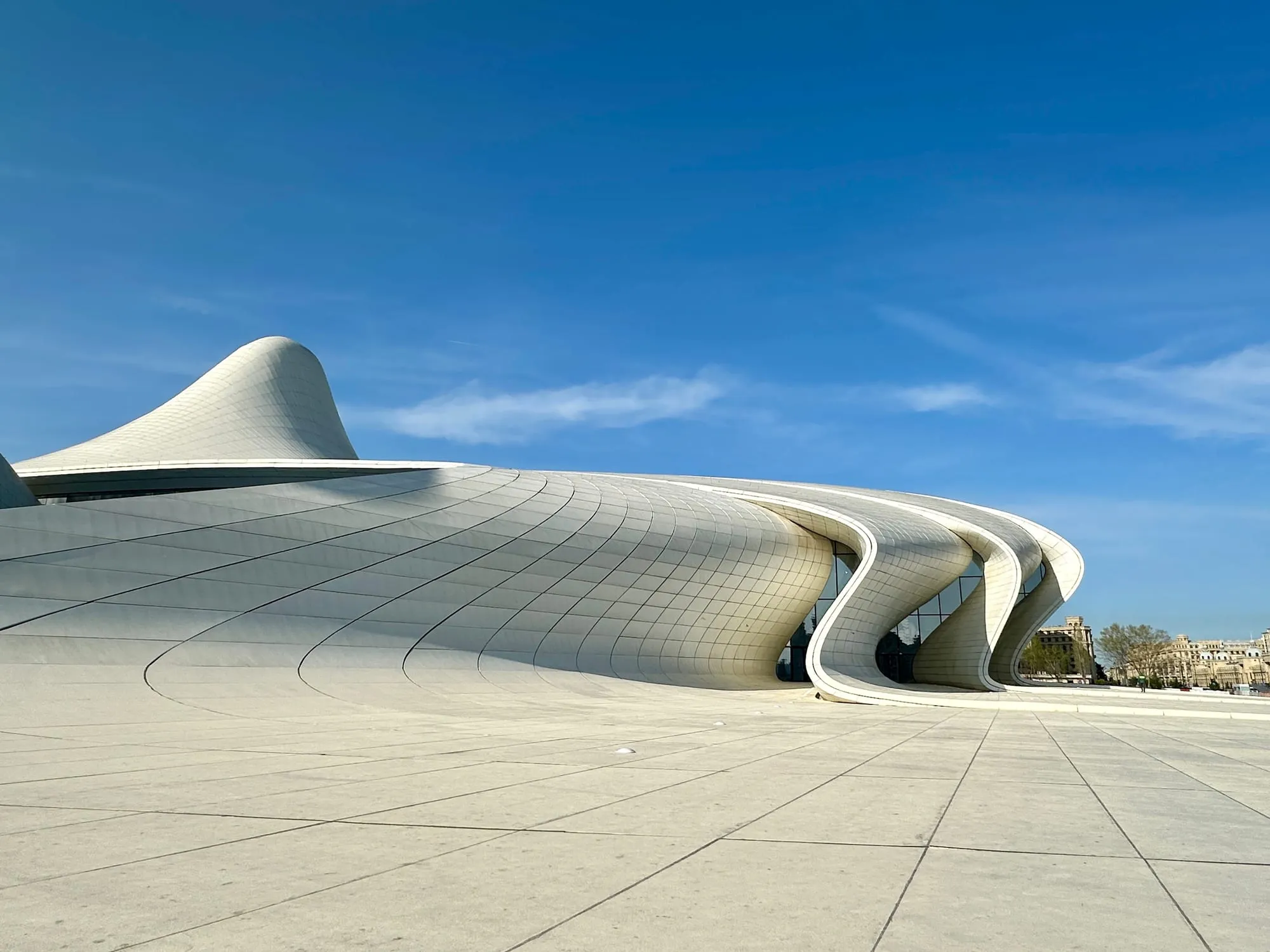 Untersicht auf das weiss geschwungene Heydar-Aliyev-Zentrum unter blauem Himmel.