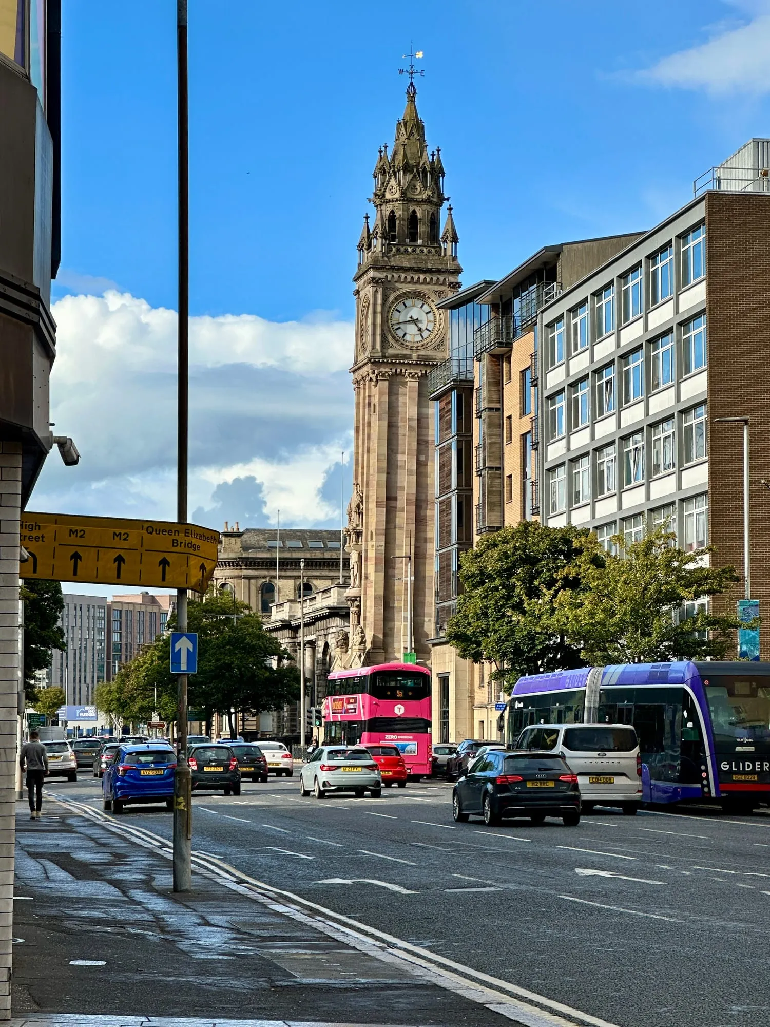 Der neugotische Albert Memorial Clock Tower in Belfast, davor ein Doppeldeckerbus und ein Glider-Schnellbus.