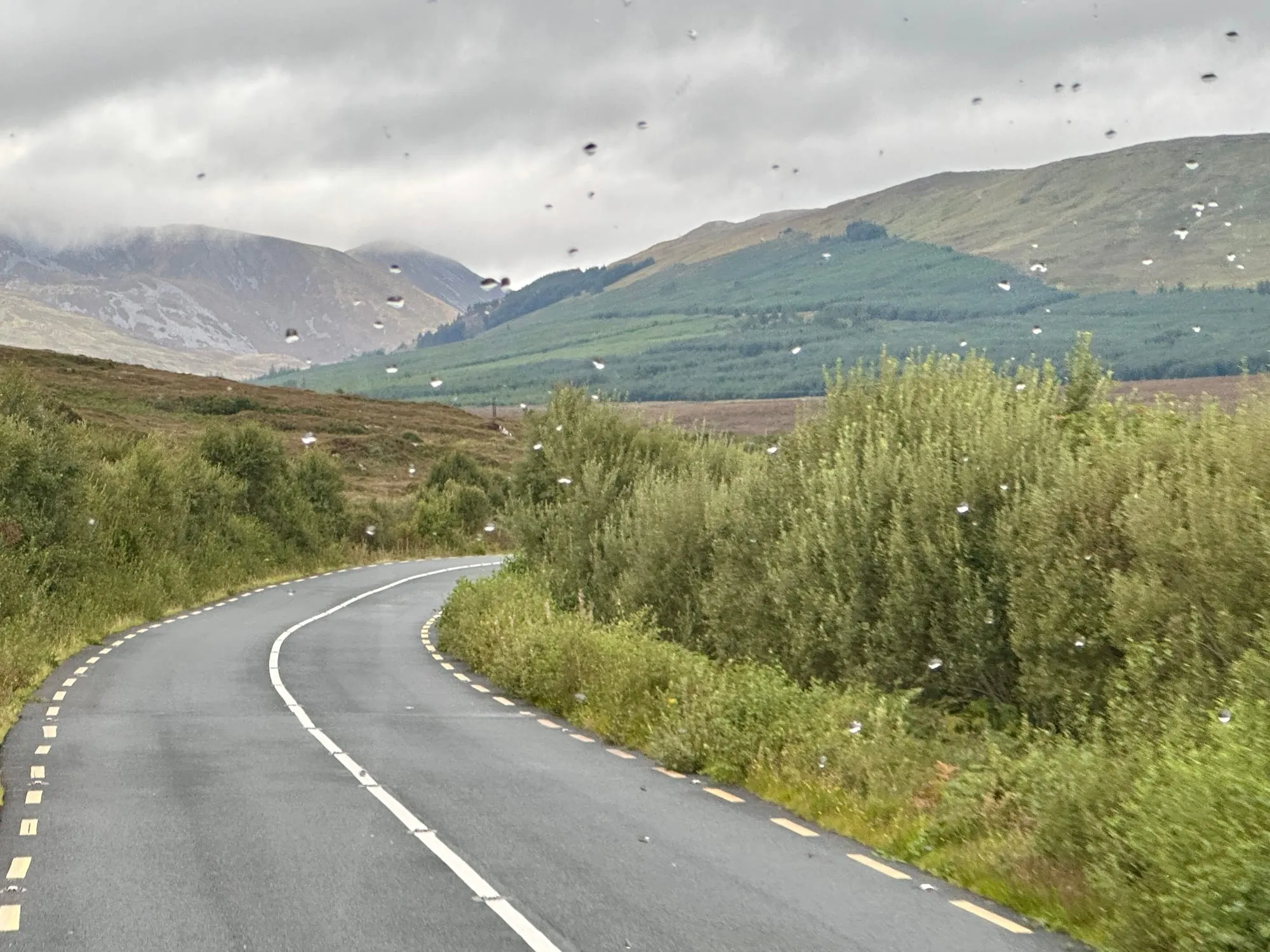 Zweispurige Landstrasse, die sich durch grüne Hügel und Moorland in Donegal windet.