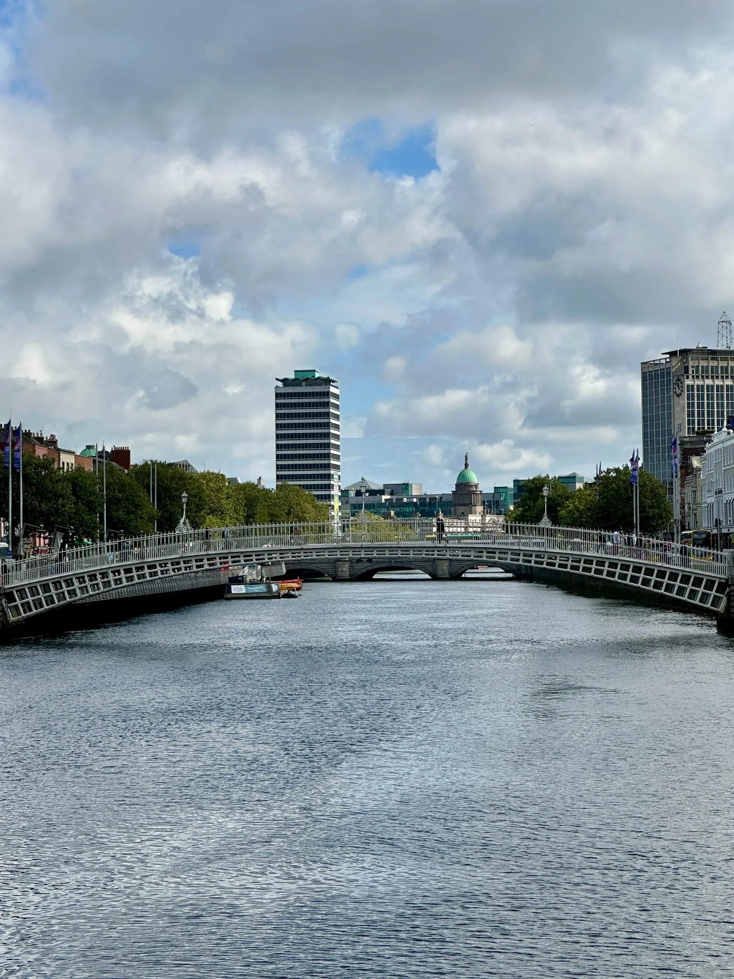 Die gusseiserne Ha'penny Bridge über den Fluss Liffey in Dublin, dahinter die Kuppel des Custom House.