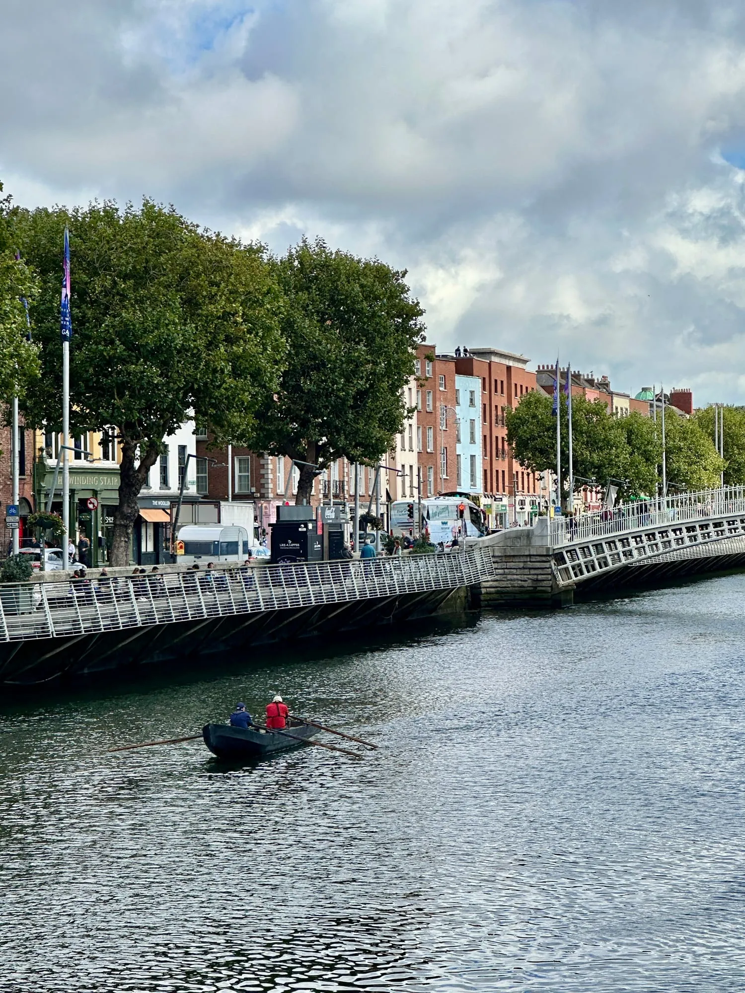 Ruderboot auf dem Fluss Liffey in Dublin, dahinter die Kaimauern der Innenstadt.