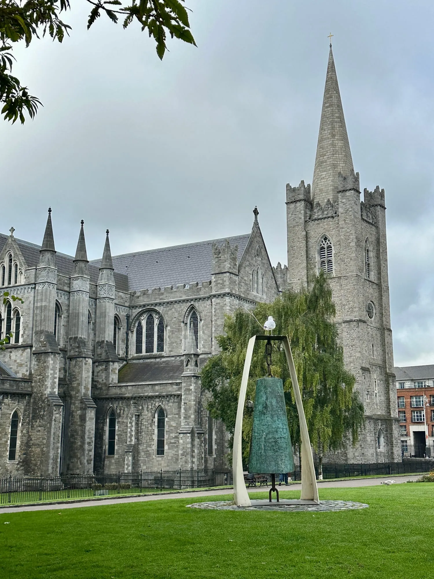 Turm und Langhaus der St Patrick's Cathedral in Dublin über einer Rasenfläche.