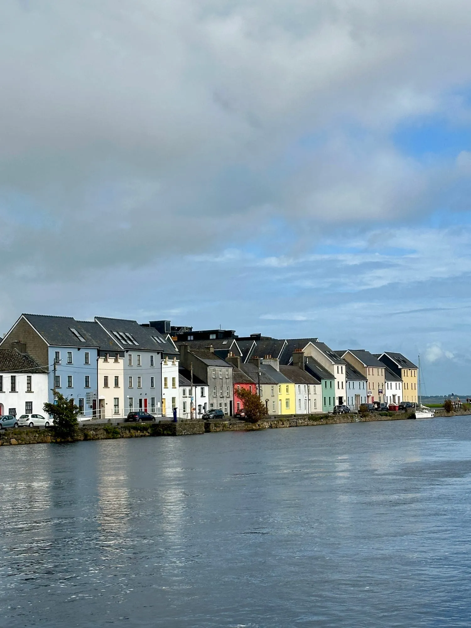 Reihe bunt gestrichener Häuser am Wasser entlang des Long Walk in Galway.