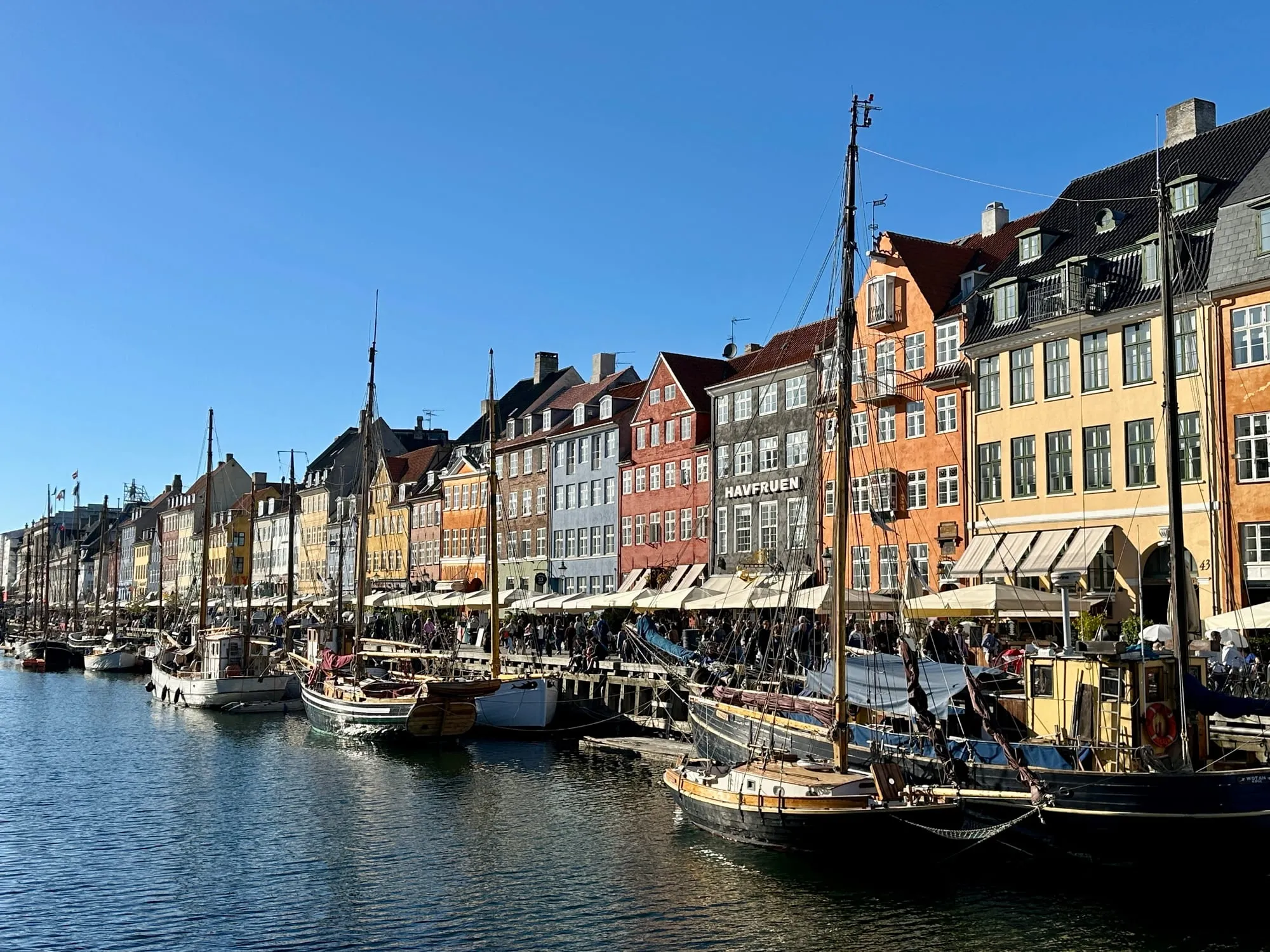 Historische Holzsegler im Kanal von Nyhavn vor bunten Häuserfassaden.