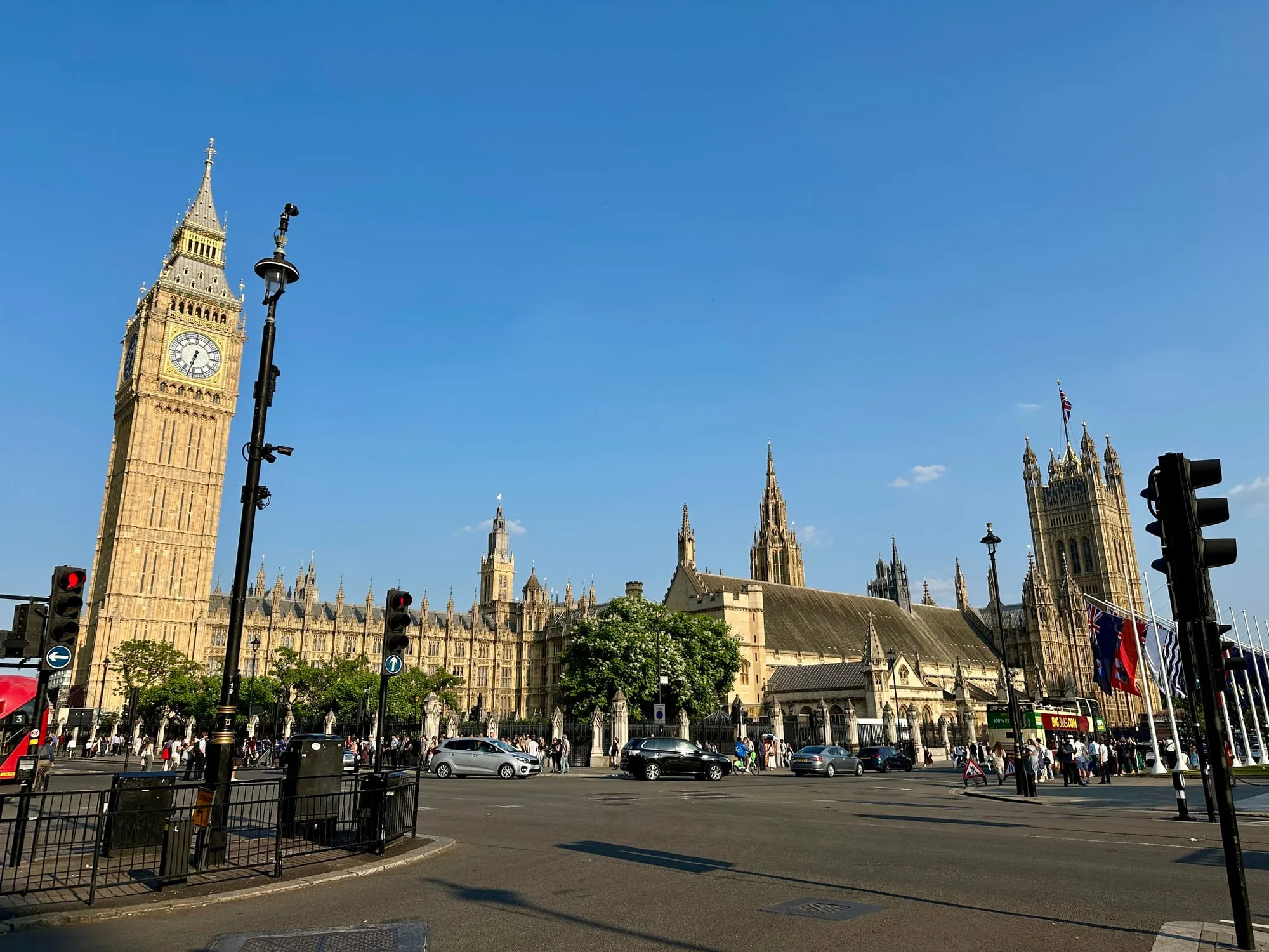 Elizabeth Tower und die Houses of Parliament vom Parliament Square aus, davor eine Kreuzung mit Ampeln.