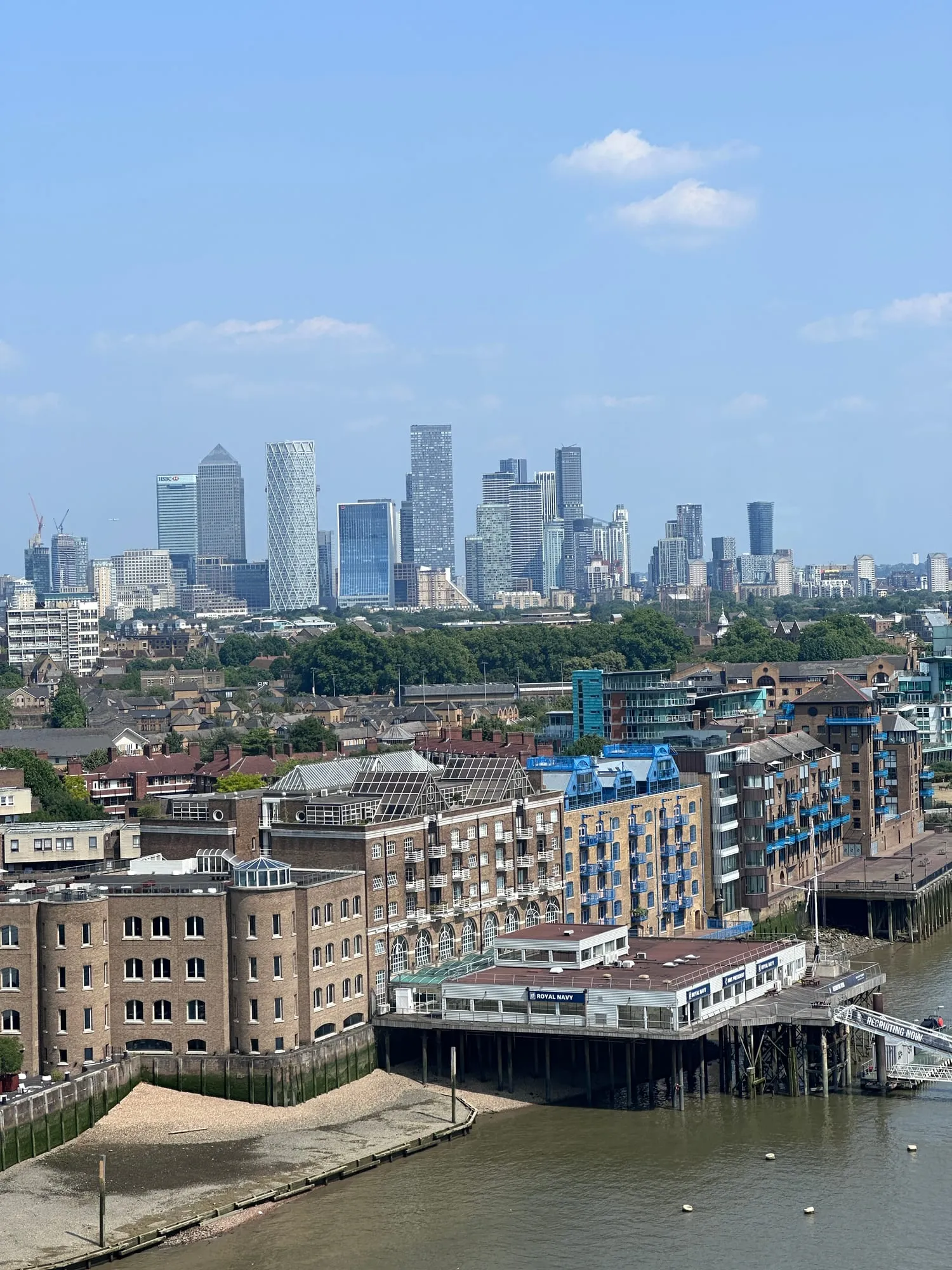 Blick über die Themse auf die Uferbebauung und die Hochhäuser von Canary Wharf am Horizont.