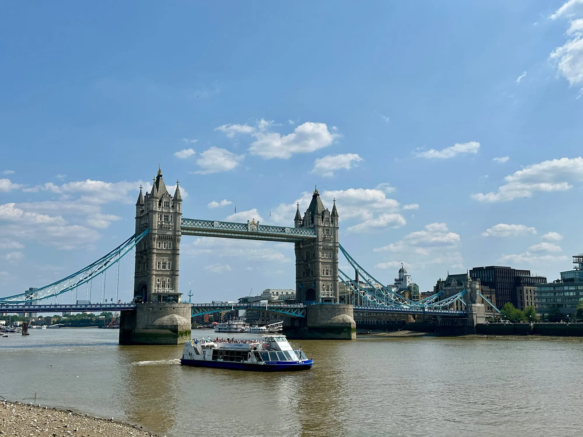 Tower Bridge über der Themse mit blauem Himmel und Booten auf dem Wasser.