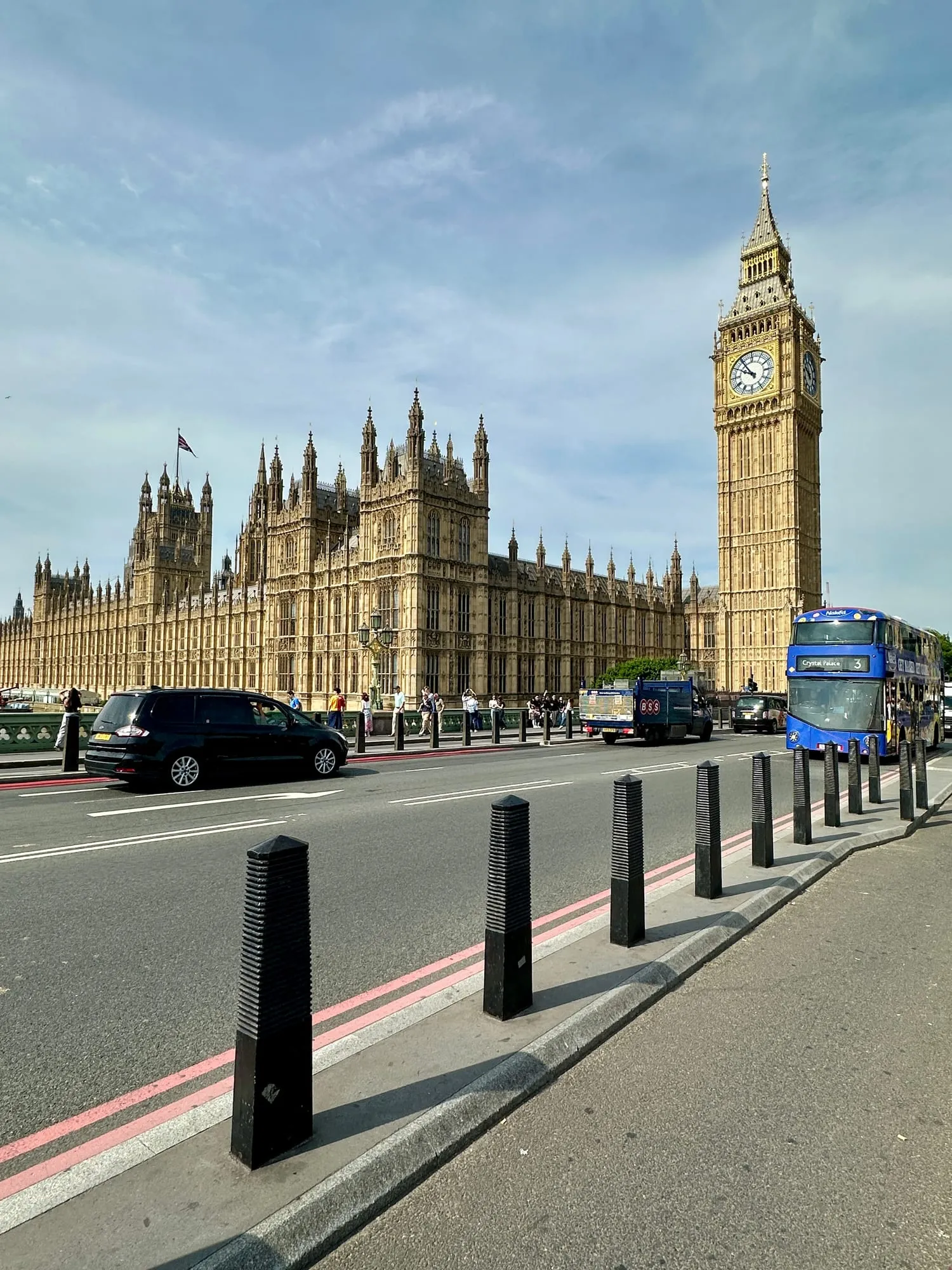 Blick von der Westminster Bridge auf die Houses of Parliament und den Elizabeth Tower, davor ein blauer Doppeldeckerbus.