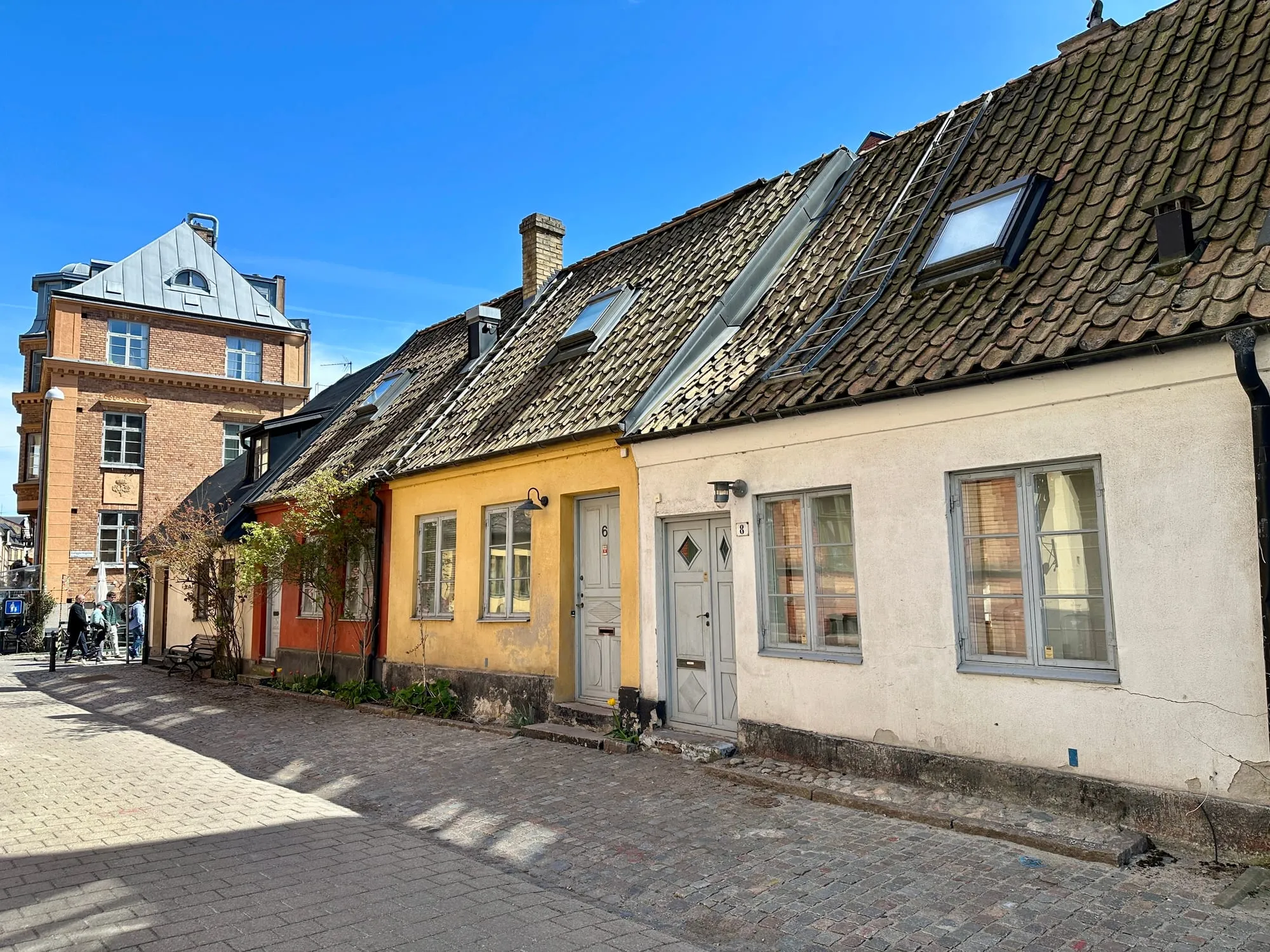 Kopfsteingepflasterte Gasse mit niedrigen bunten Häusern im Malmöer Altstadtviertel Gamla Väster.